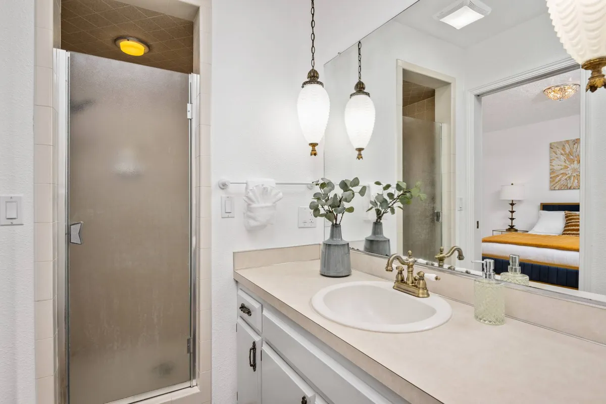 A modern, tranquil bathroom with a stylish sink, sleek fixtures, glass-enclosed shower, and fresh decorative plants. The space is bright and calming, designed for relaxation and everyday routines.