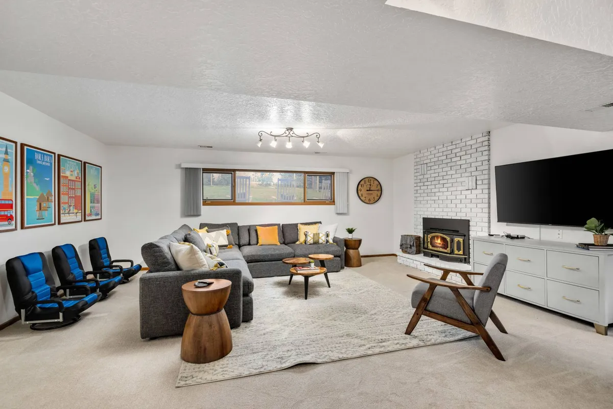 A spacious and cozy media room with a large sectional sofa, a fireplace, and a round coffee table. The space is designed for relaxing, watching movies, or gathering with friends and family, creating the perfect setting for game nights or movie marathons.